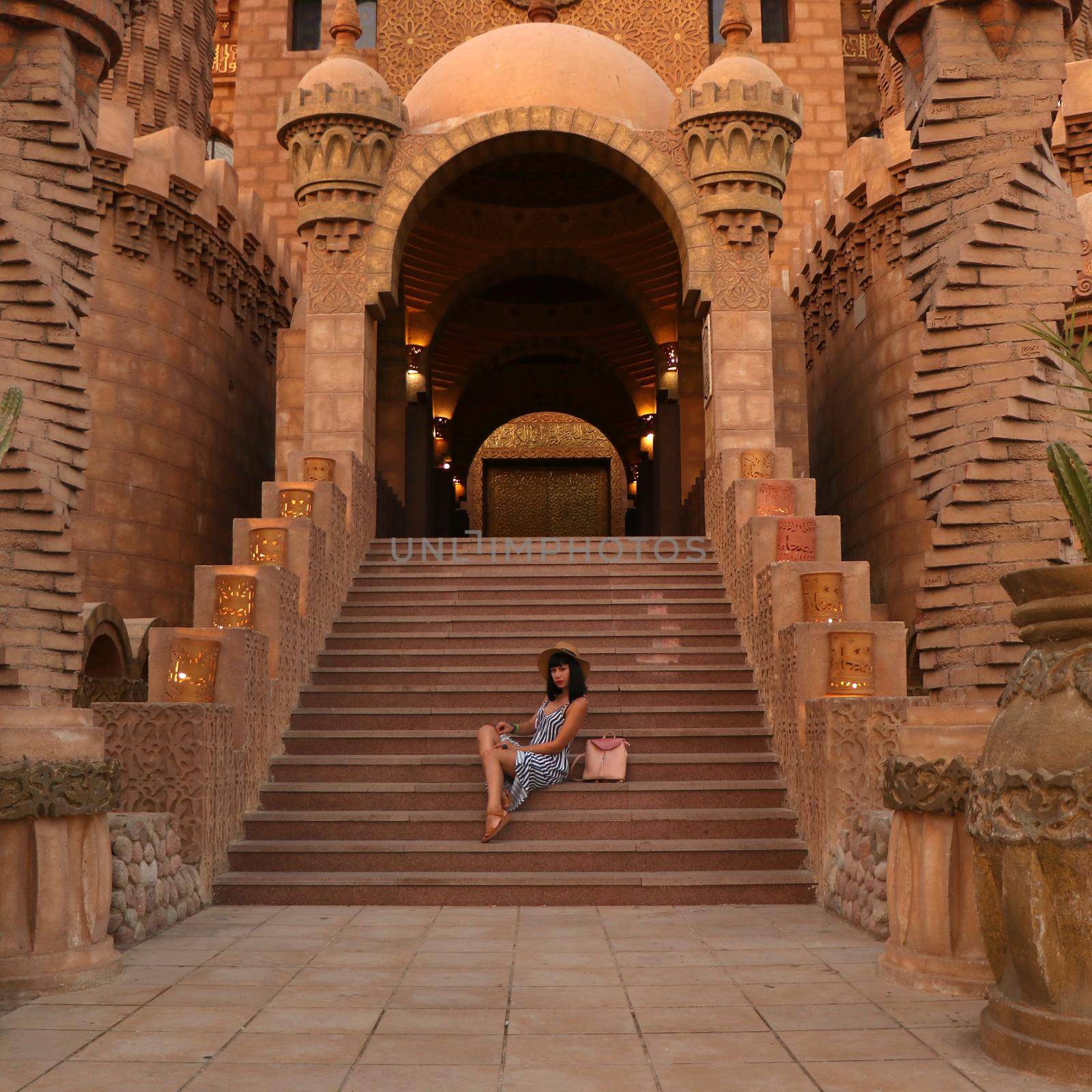 young girl on the background of the El Mustafa Mosque in the Old City of Egypt. woman sits on the steps of a mosque. Travel to Egypt concept. An ancient mosque in the tourist city of Sharm El Sheikh