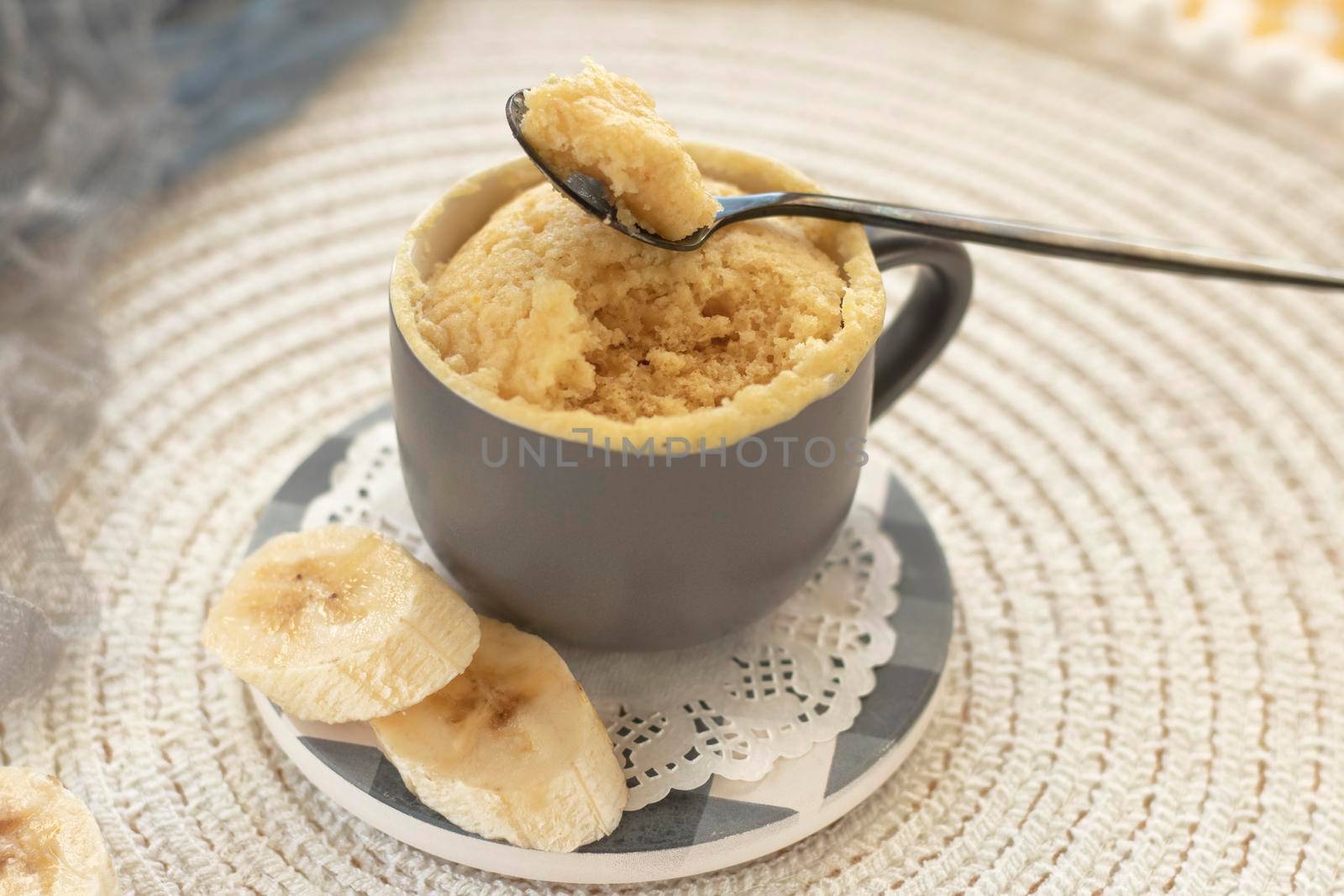 cupcake in a mug with banana pieces. Banana cupcake on a light background. vanilla biscuit in a mug. The concept of a dessert in the microwave. bananas cake. High quality photo