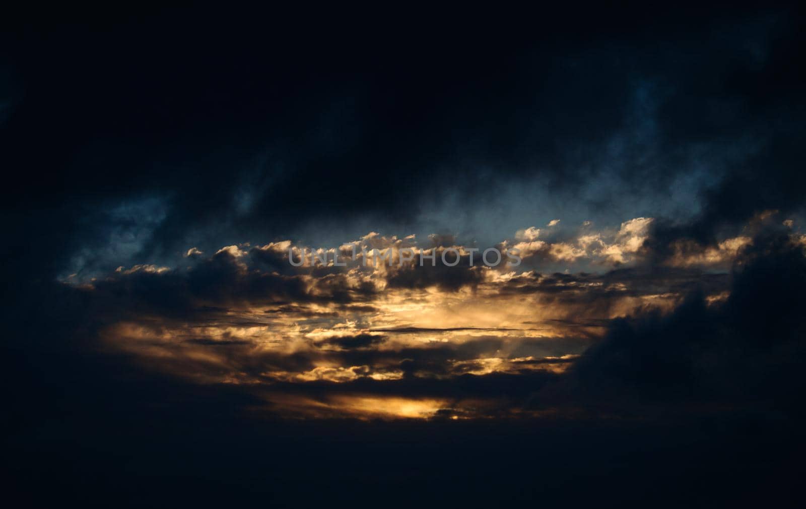 Dramatic dark evening sky landscape with moody clouds and golden sunlight