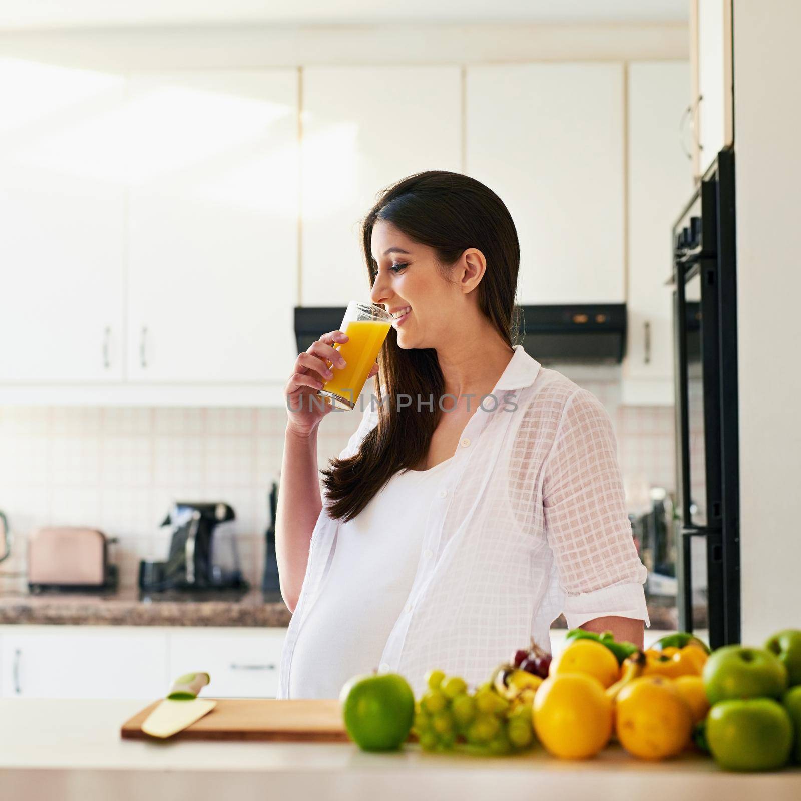 Healthy living equals a healthy baby. Shot of young pregnant woman drinking a glass of orange juice at home. by YuriArcurs