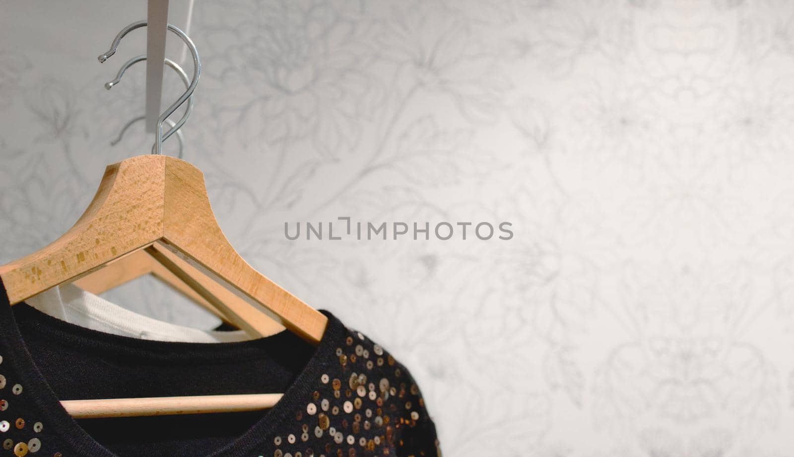 Wooden clothes hangars on a rail against a bright white wallpaper background by tennesseewitney
