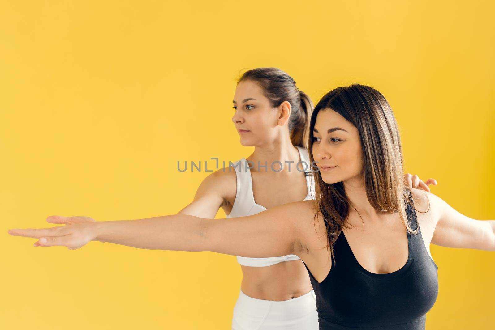 Beautiful woman practicing yoga, conducting a training session with female students, showing the correct execution of Virabhadrasana exercise, warrior pose. Training concept. by etonastenka