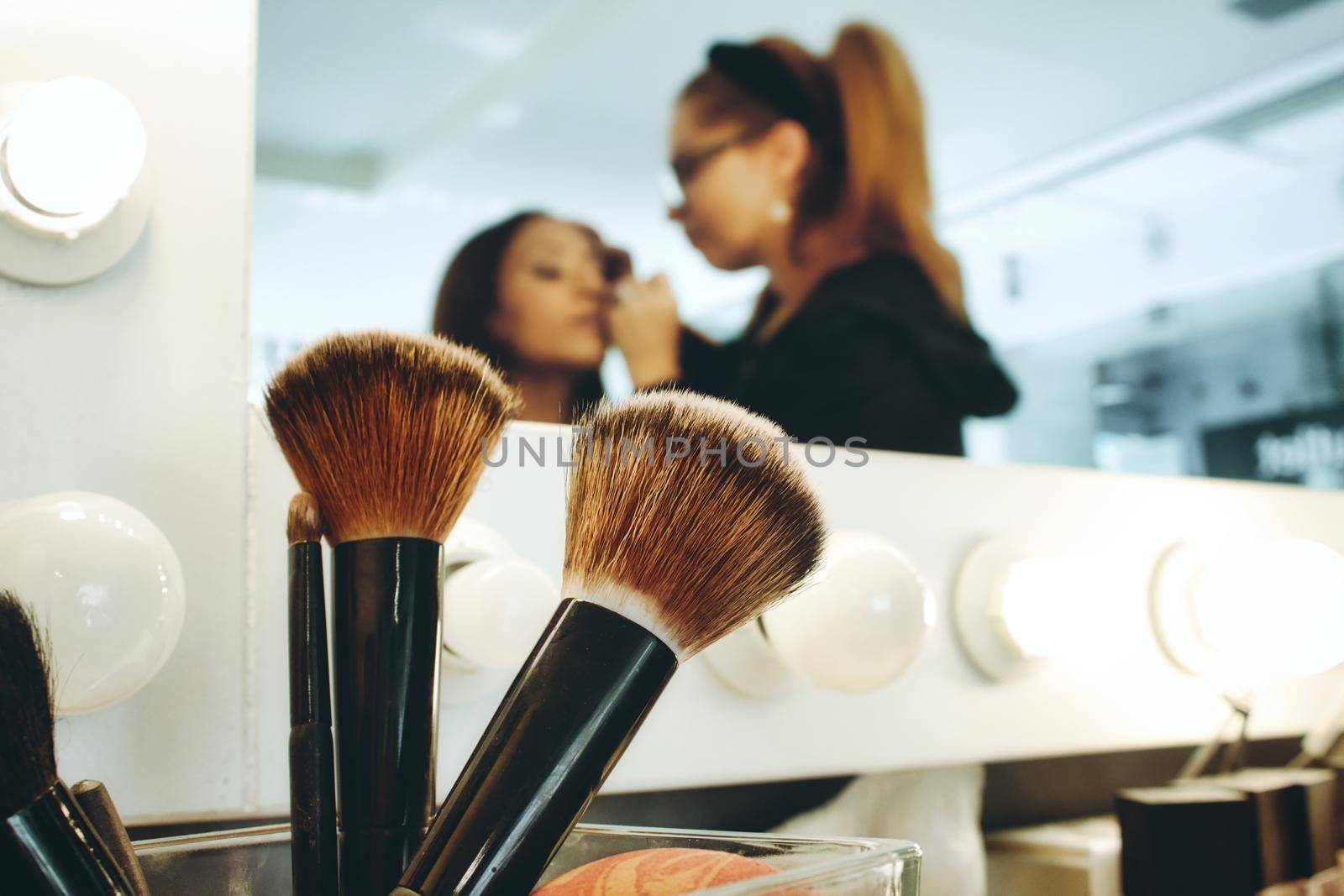 Closeup of accessory brushes with a professional make-up artist in a studio painting a woman's face