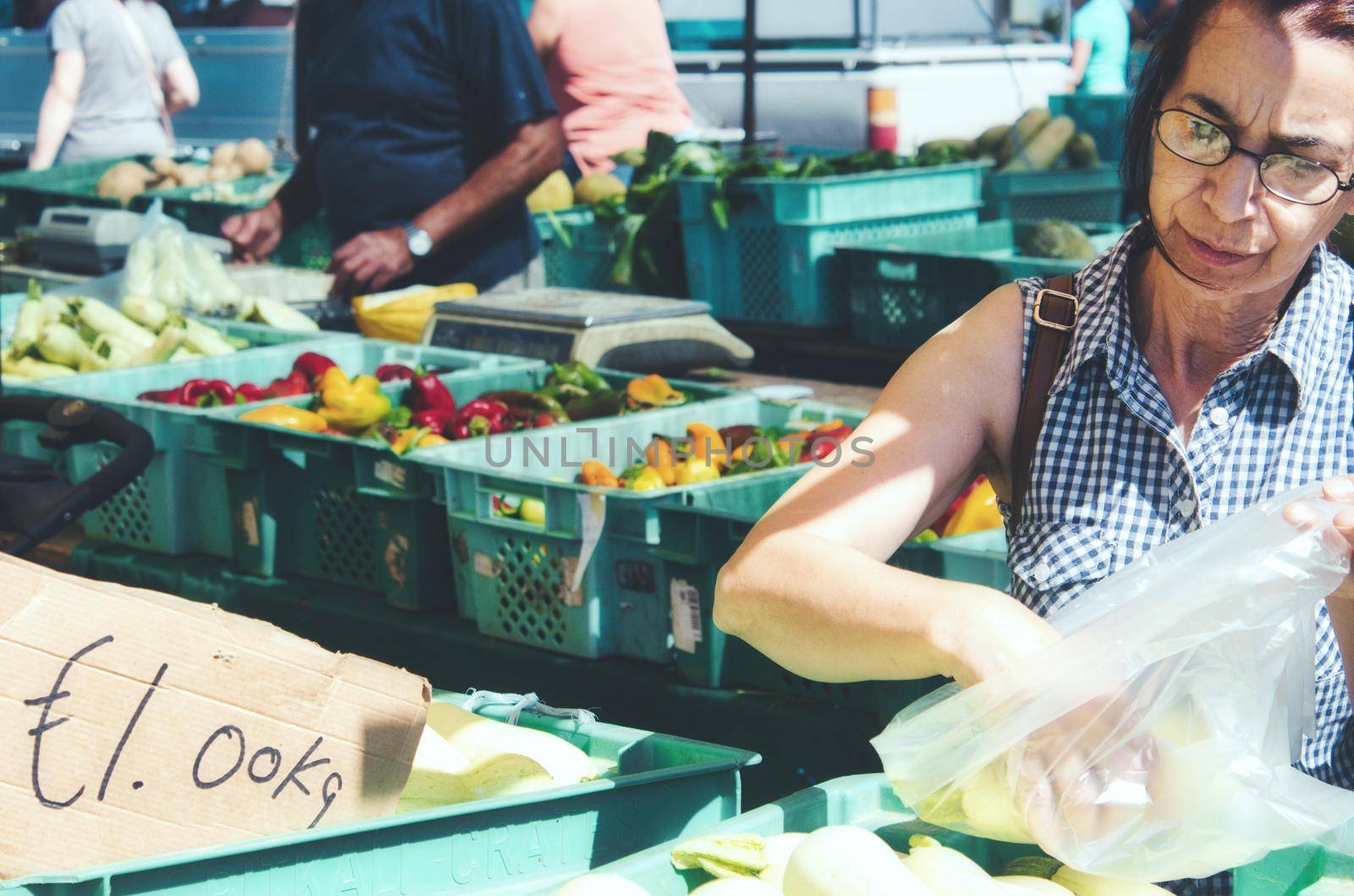 Middle-aged woman buying fresh vegetables at an open-air market stall