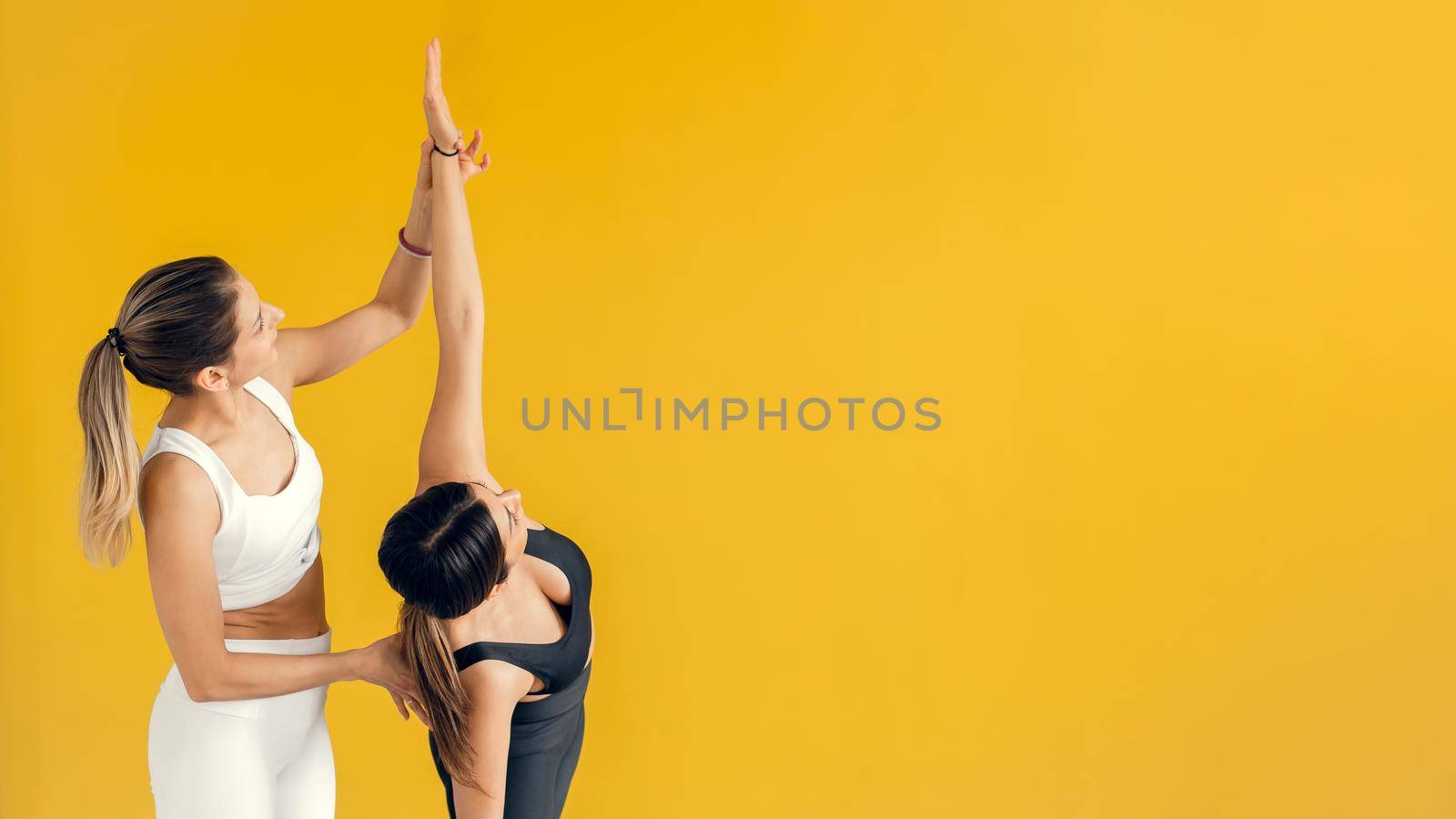 Yoga class instructor helps beginner to make asana exercises. Happy yoga class with a trainer. Exercise control. Web banner by etonastenka
