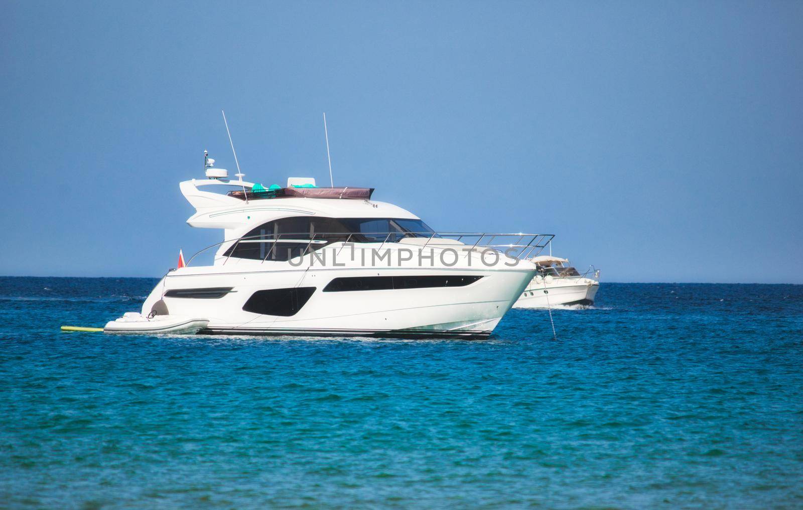 A luxury yacht sailing on the sea with clear blue sky and horizon visible in the background