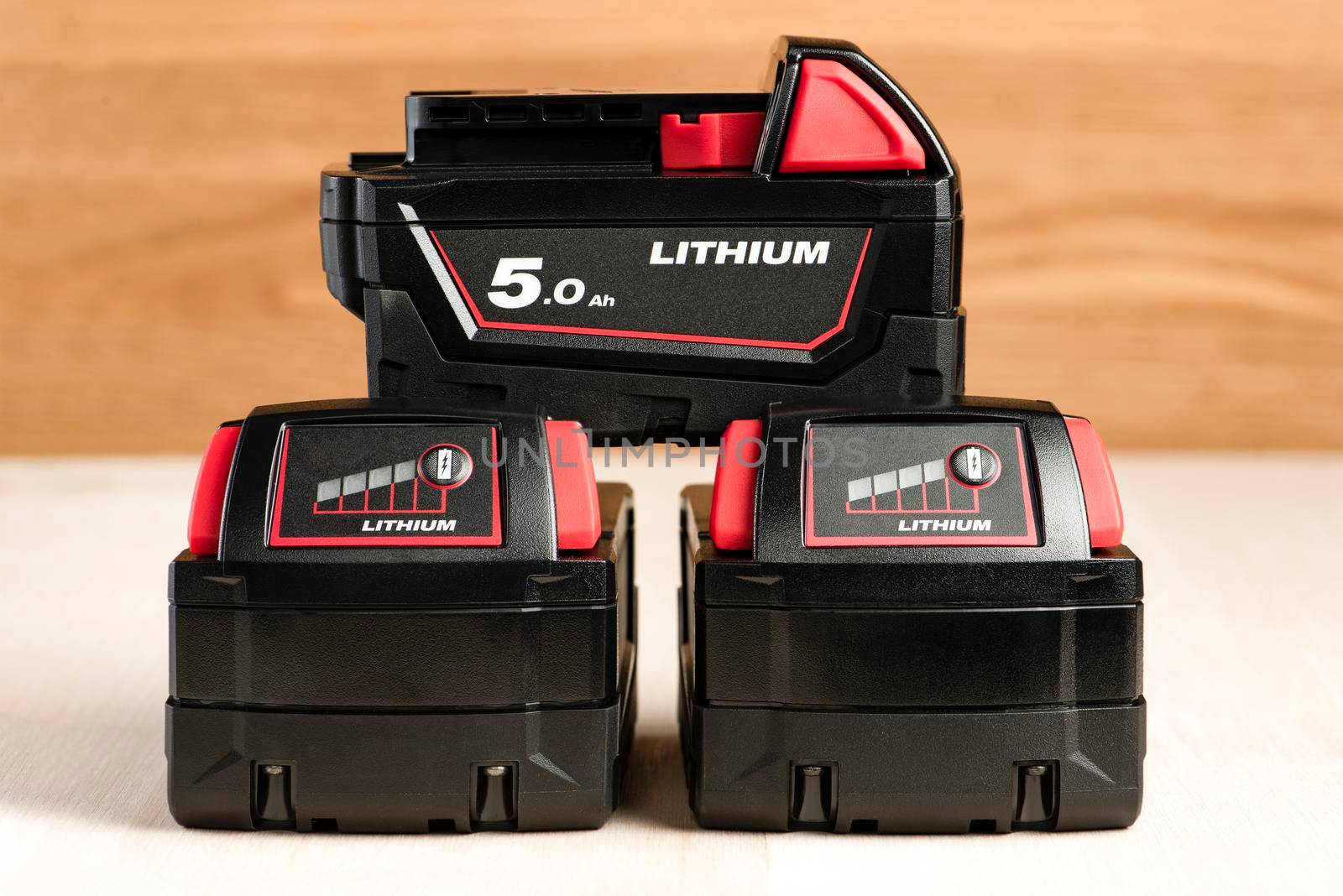 Lithium battery for cordless drill. Screwdriver battery. Four batteries with a charge indicator lie on a wooden background by SERSOL