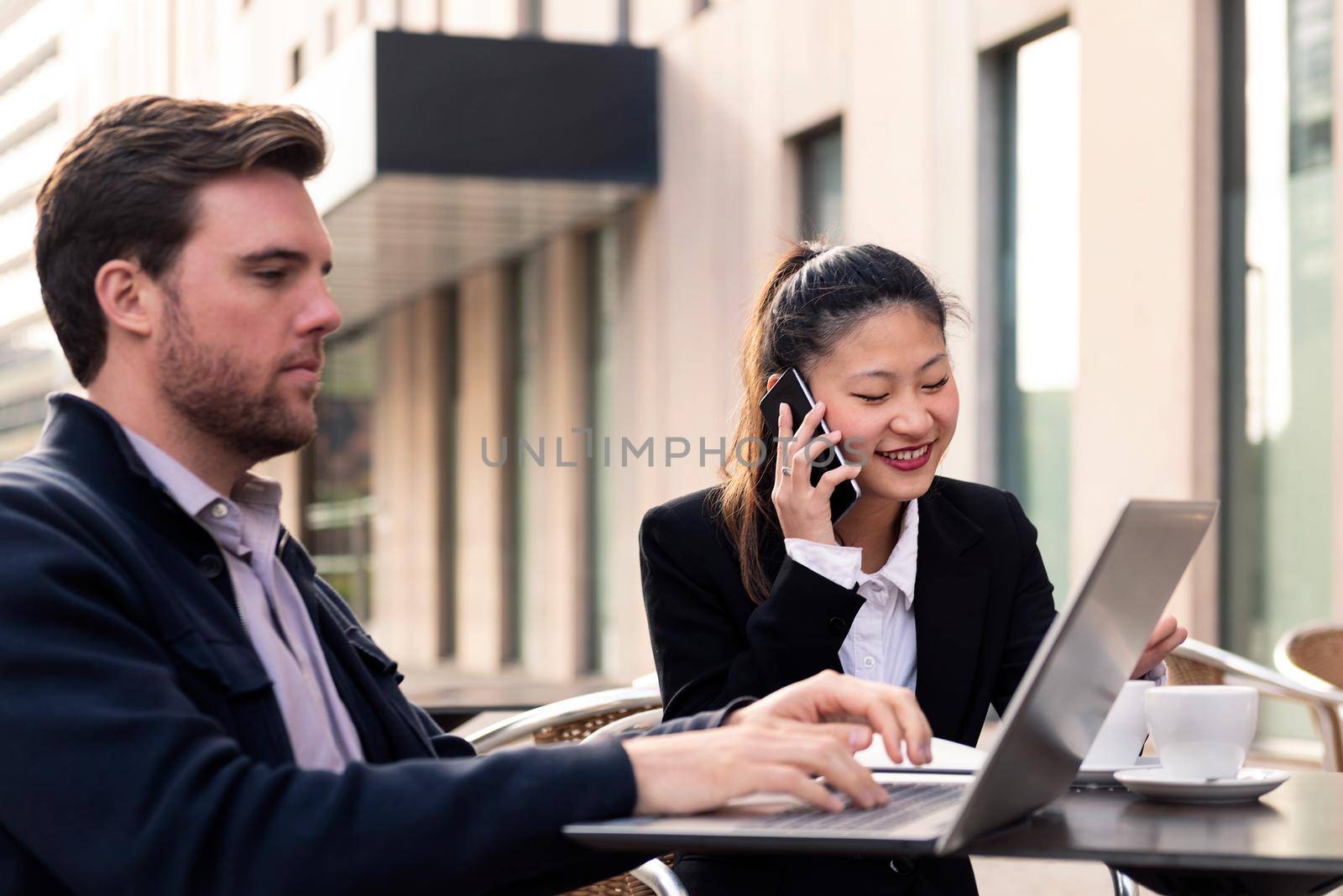 young businesswoman talking by phone while has a work meeting with his partner on a terrace in the financial district, concept of entrepreneurship and business