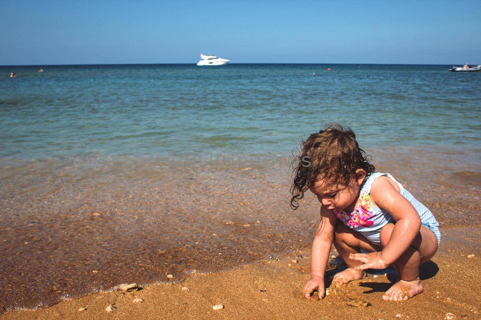 Little girl playing on a sandy beach by the sea