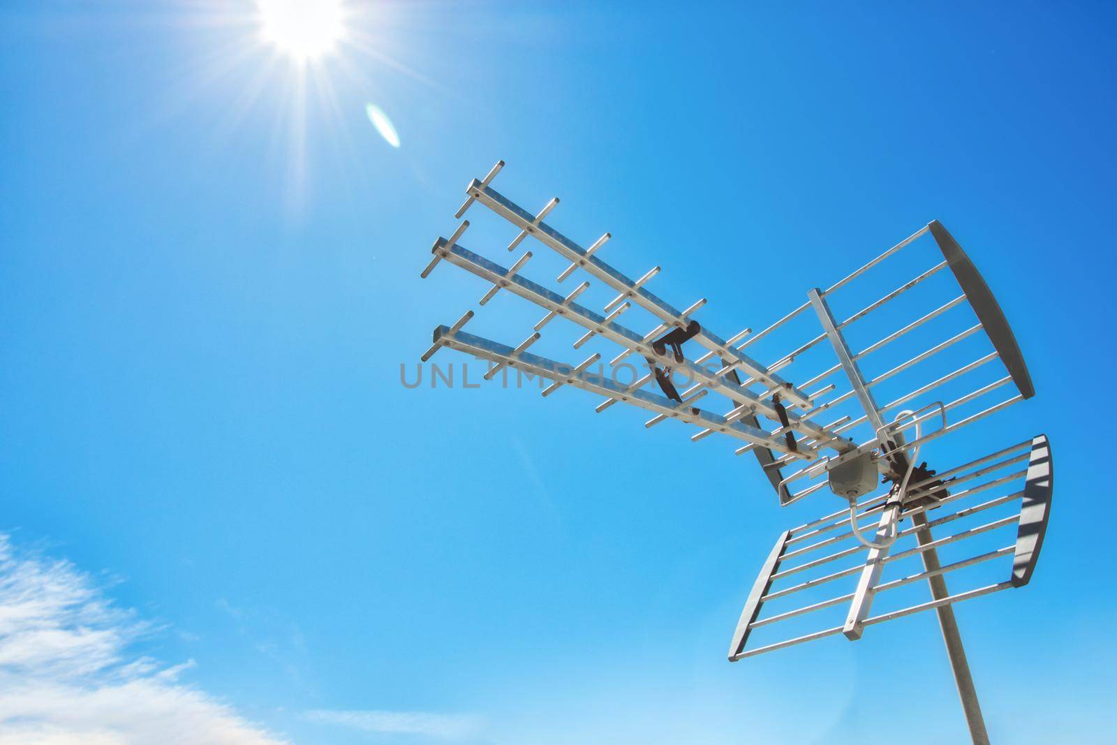 Television antenna on a rooftop against a clear sunny blue sky