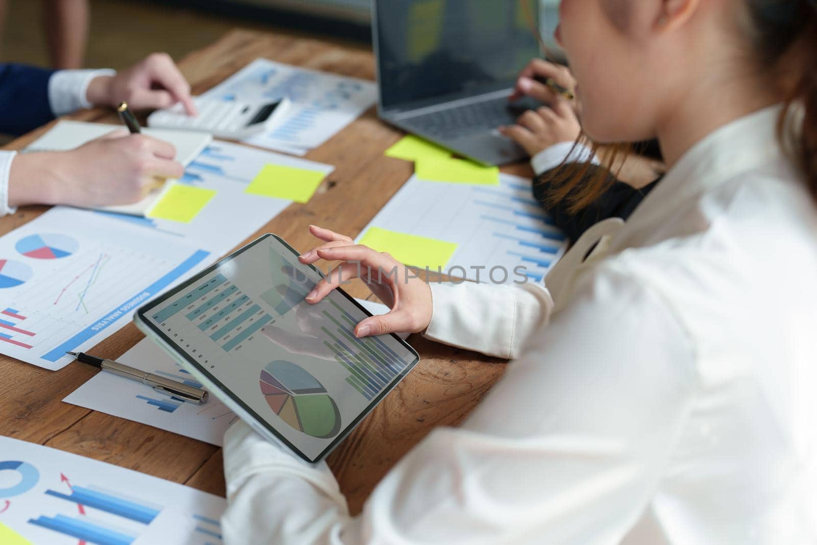 Businesswoman using a tablet to discuss marketing strategy summaries with colleagues in meetings, teamwork, investment planning.
