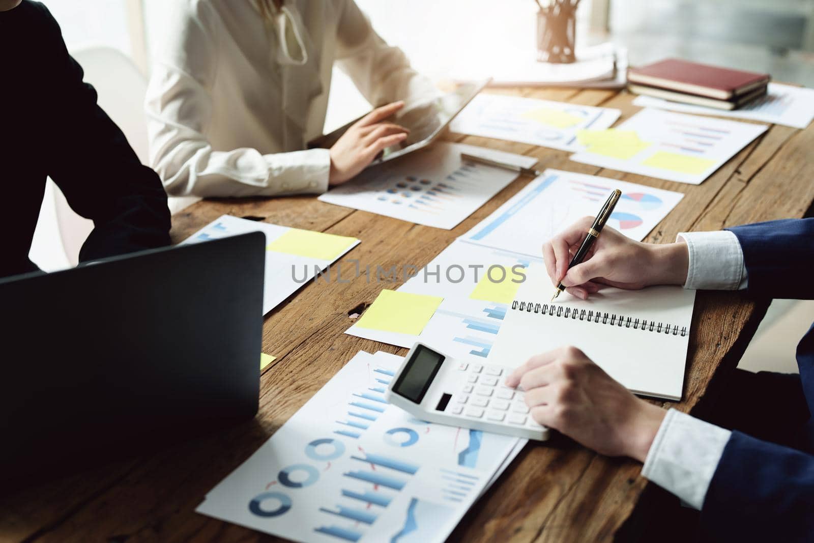 Male businessman holding pen to take notes summarizing marketing strategy with female colleagues in meeting, teamwork, investment planning.