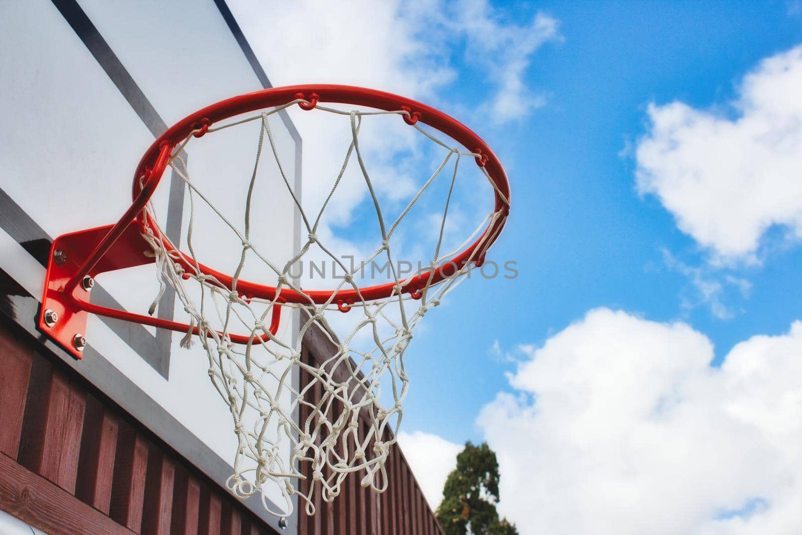 Basketball hoop with netting from underneath with a blue sky background