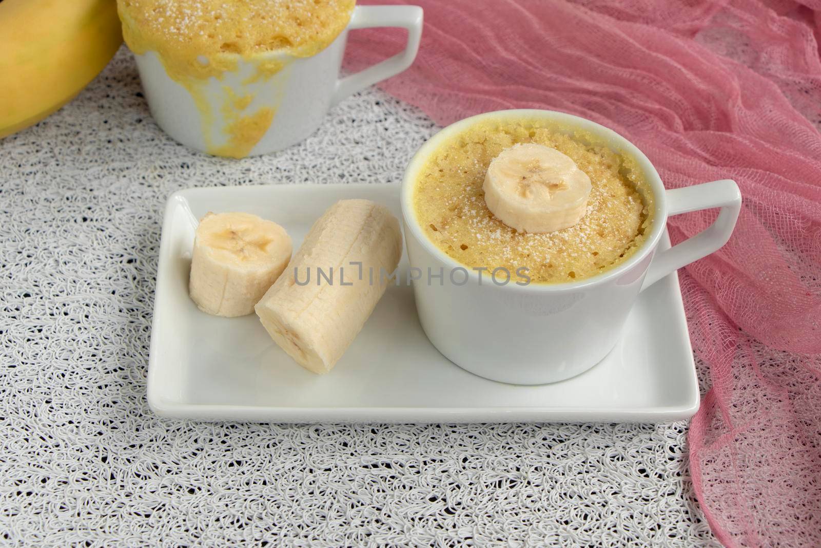 cupcake in a mug with banana pieces. Banana cupcake on a light background. The concept of a dessert in the microwave. bananas cake. High quality photo