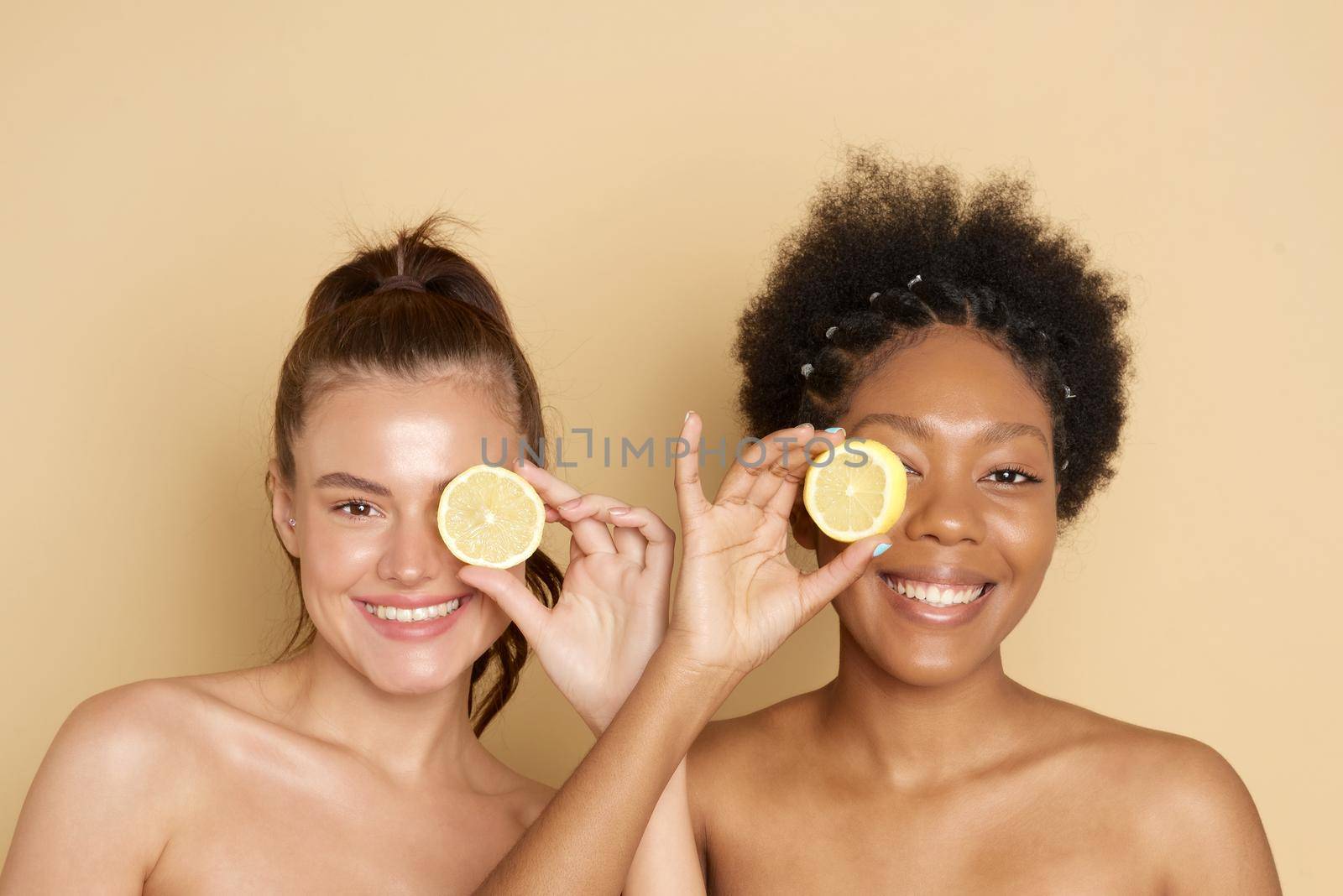 Colorful citrus circles near the face of cheerful multiracial women smiling and holding fresh citrus fruits near eyes while representing vitamin C benefits.