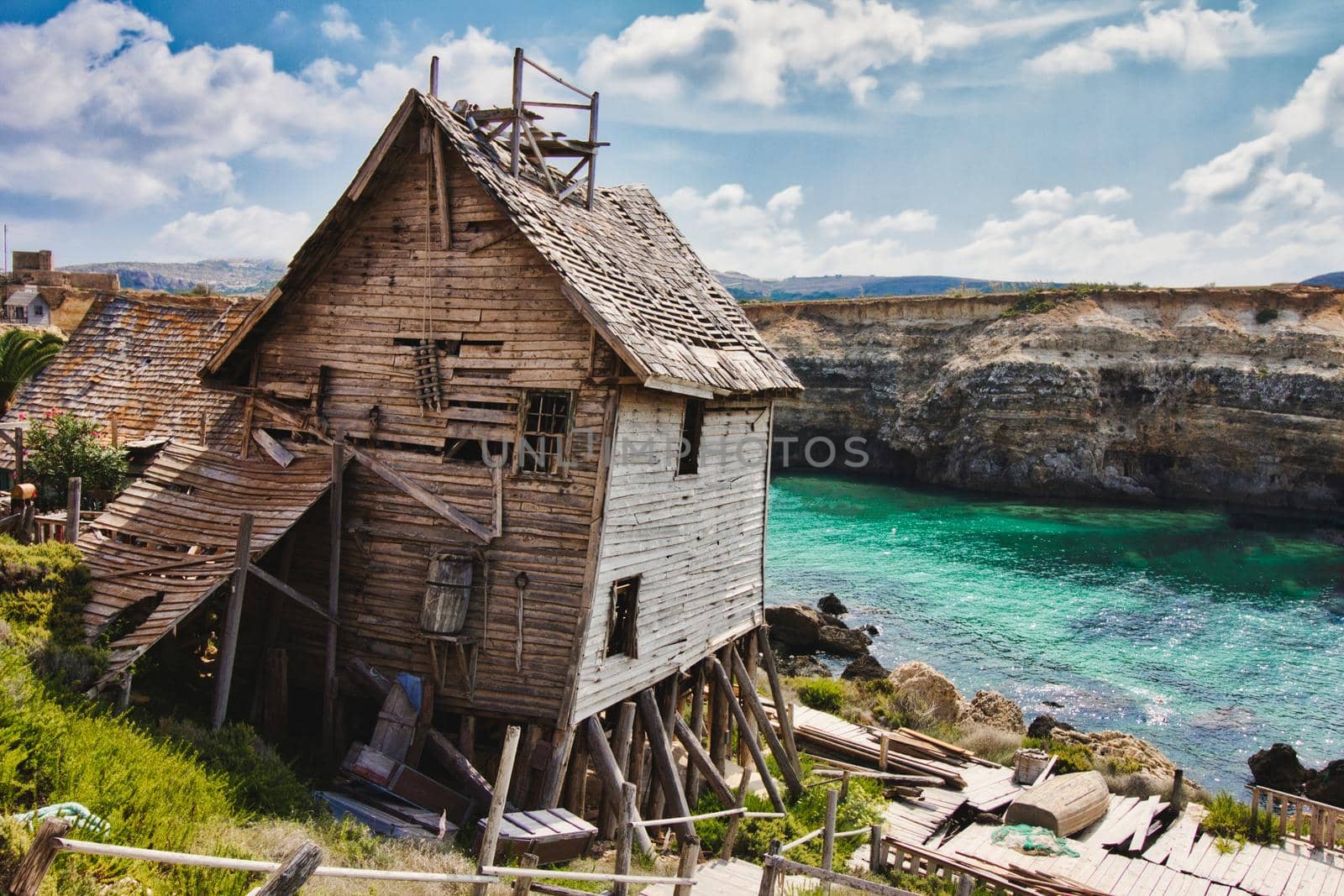 Old abandoned house on the edge of a cliff overlooking the sea and cliffs in the background