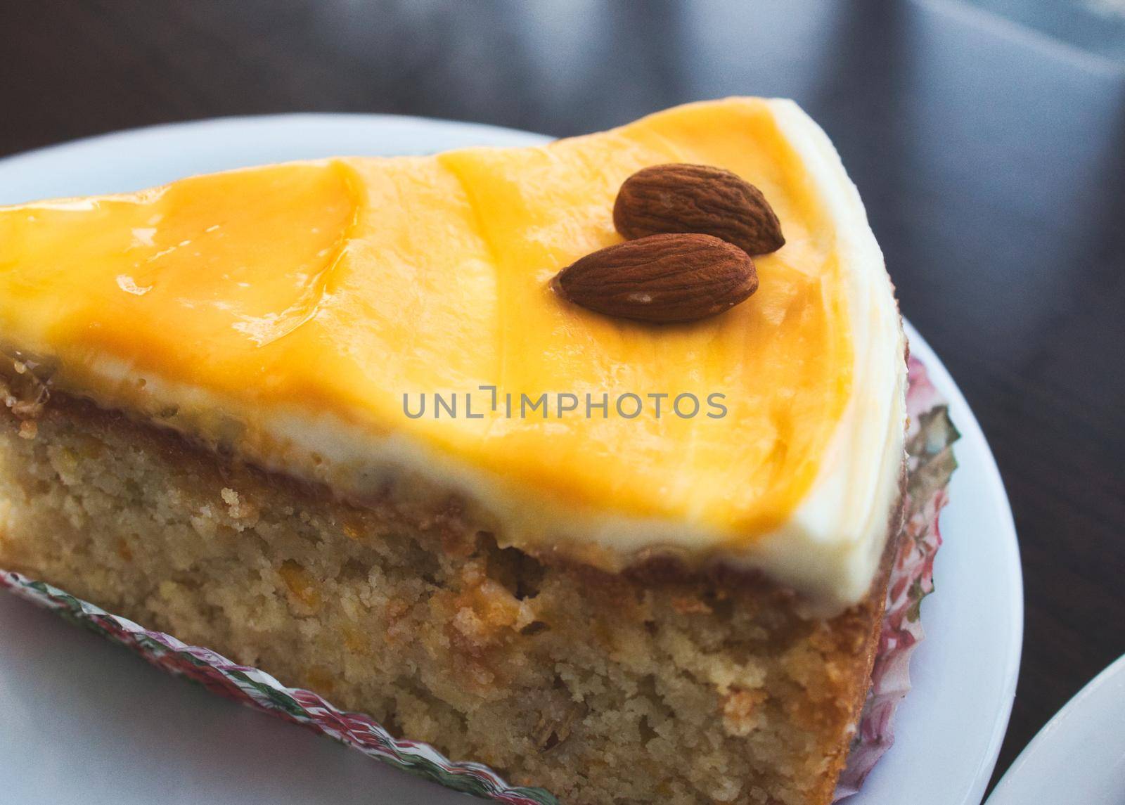 Close-up of a slice of carrot cake with orange icing and almonds on top by tennesseewitney