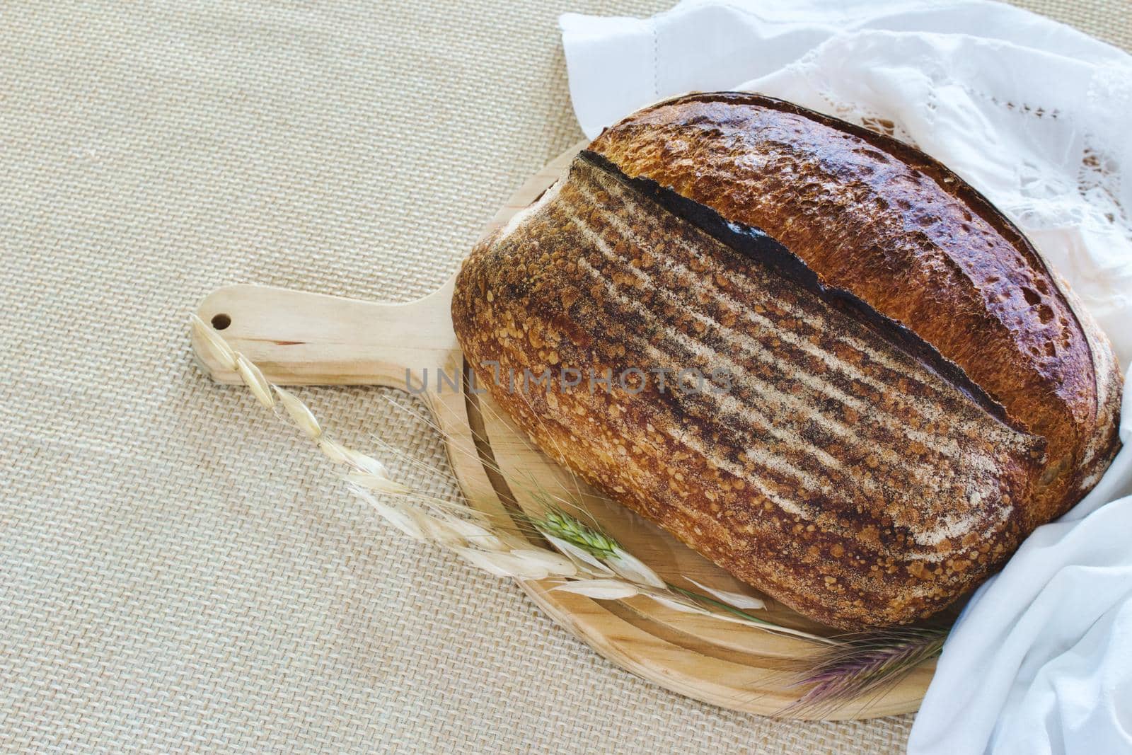 A loaf of rustic homemade wholemeal bread on a wooden chopping board