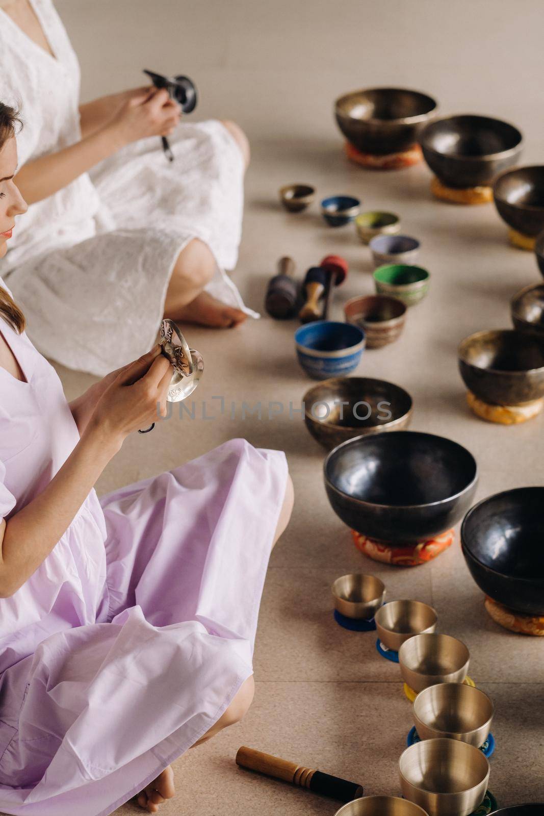 Two female yoga teachers play on Tibetan bowls in the gym during a yoga retreat.