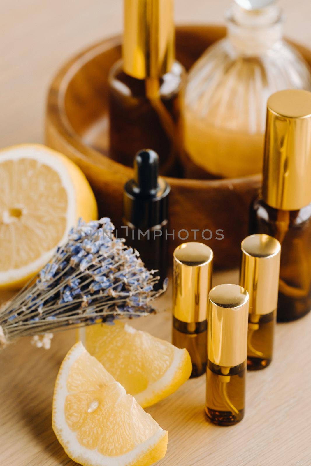 Essential oil in bottles with lemon and lavender fragrance, lying on a wooden surface.