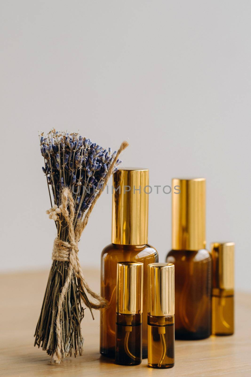 Essential oil in one bottle and dried lavender standing on the surface.