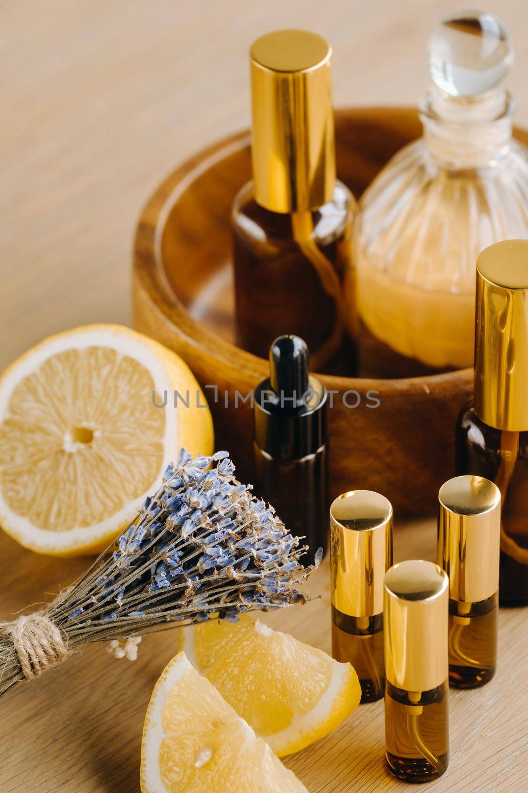 Essential oil in bottles with lemon and lavender fragrance, lying on a wooden surface.