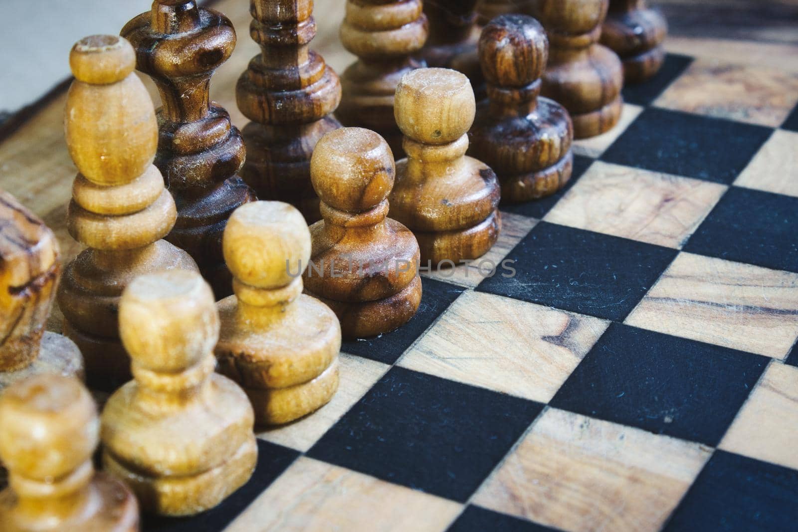 Olive wood chess pieces lined up on a wooden chequered board by tennesseewitney