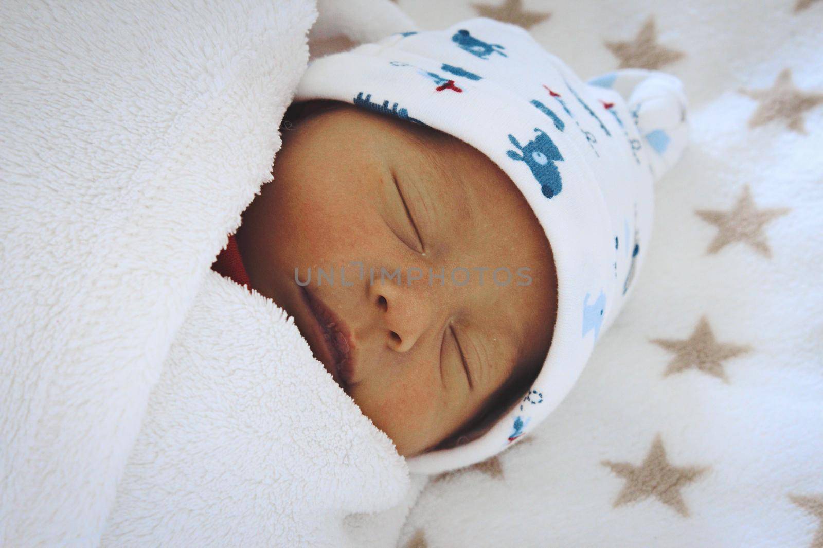 A newborn baby sleeping, wrapped up in swaddling blanket by tennesseewitney