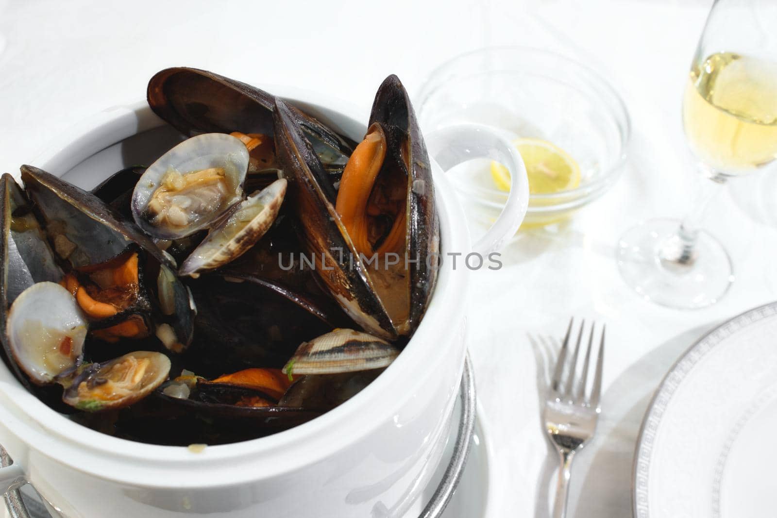 Pot of mussels and clams on a table isolated against a white tablecloth in a restaurant