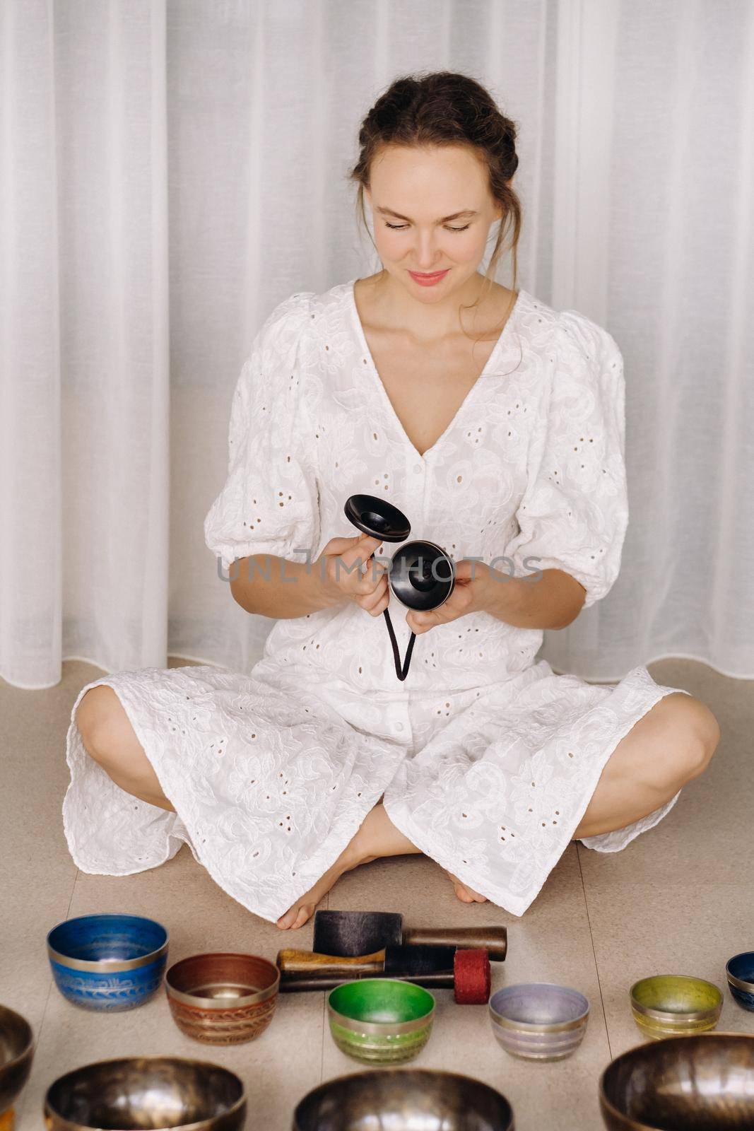 Portrait of a female yoga teacher playing a Tibetan bowl or singing a bell in the gym during a yoga retreat.