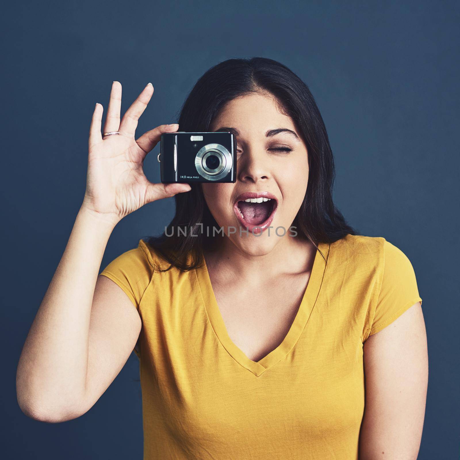 Youre so photogenic. Studio portrait of an attractive young woman taking a photo against a blue background. by YuriArcurs