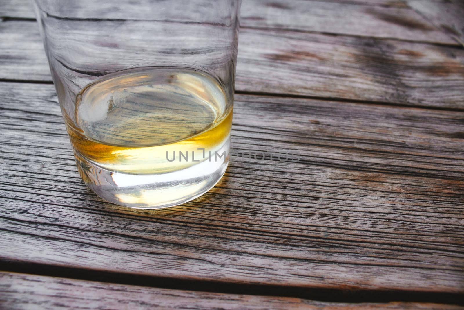 Close-up of a glass tumbler of whiskey on a wooden table