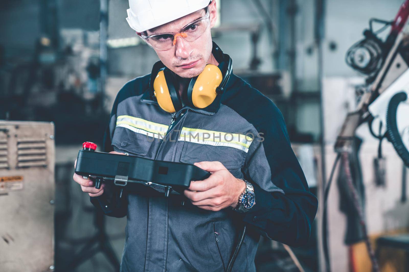 Young factory worker working with adept robotic arm in a workshop . Industry robot programming software for automated manufacturing technology .