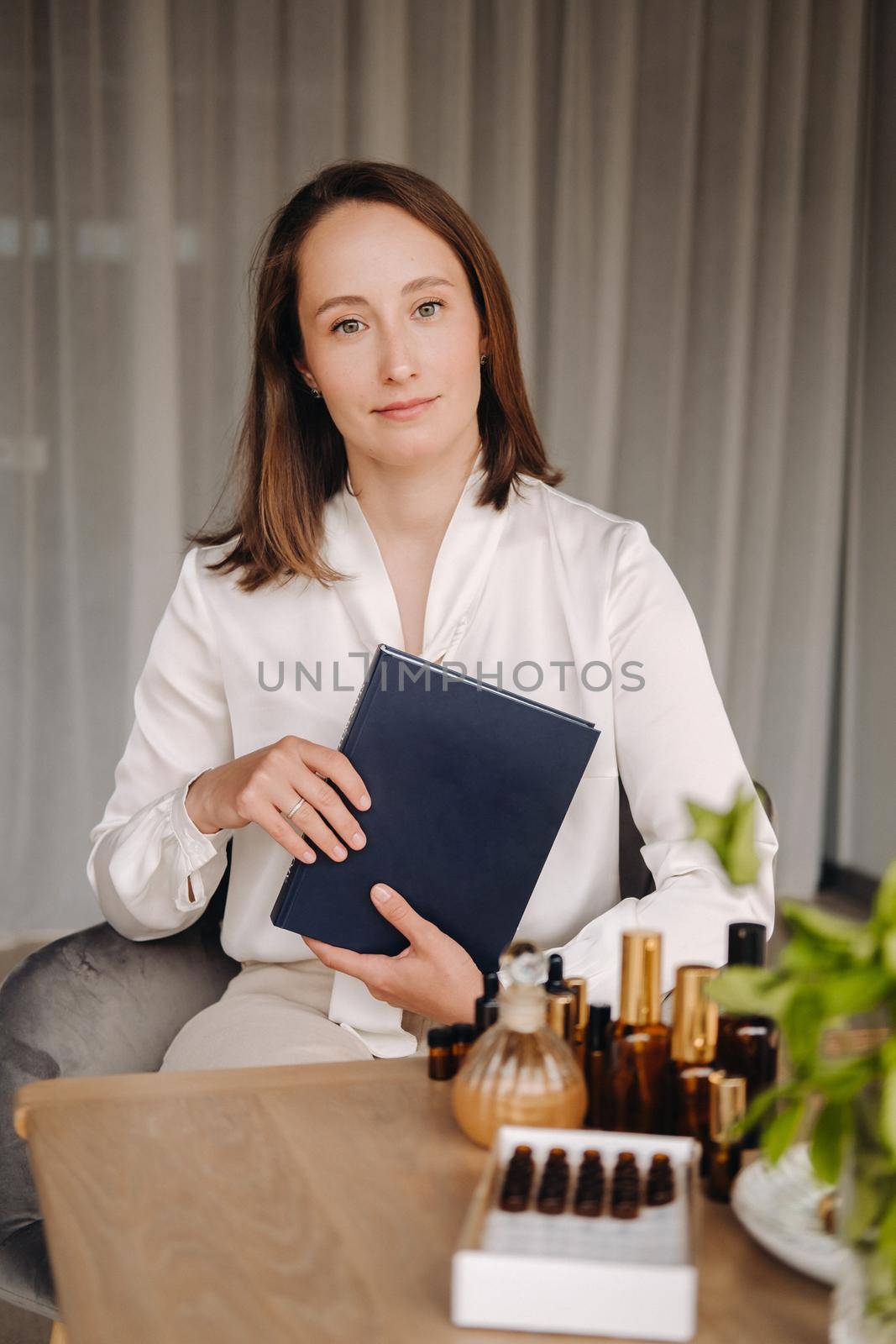 portrait of a smiling girl-woman sitting in an armchair. An aromatherapist in a white blouse is sitting in the office.