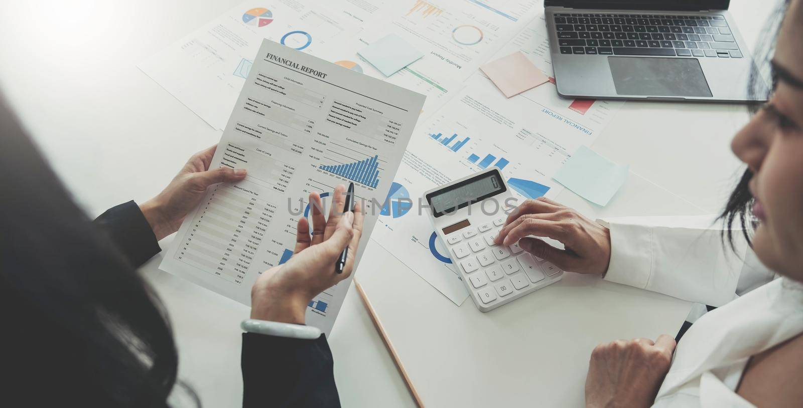 Top view of Finance business people or accountants point to the graph and use a calculator to calculate company income, expenses, taxes, and employee bonuses for Next year's improvement plan.