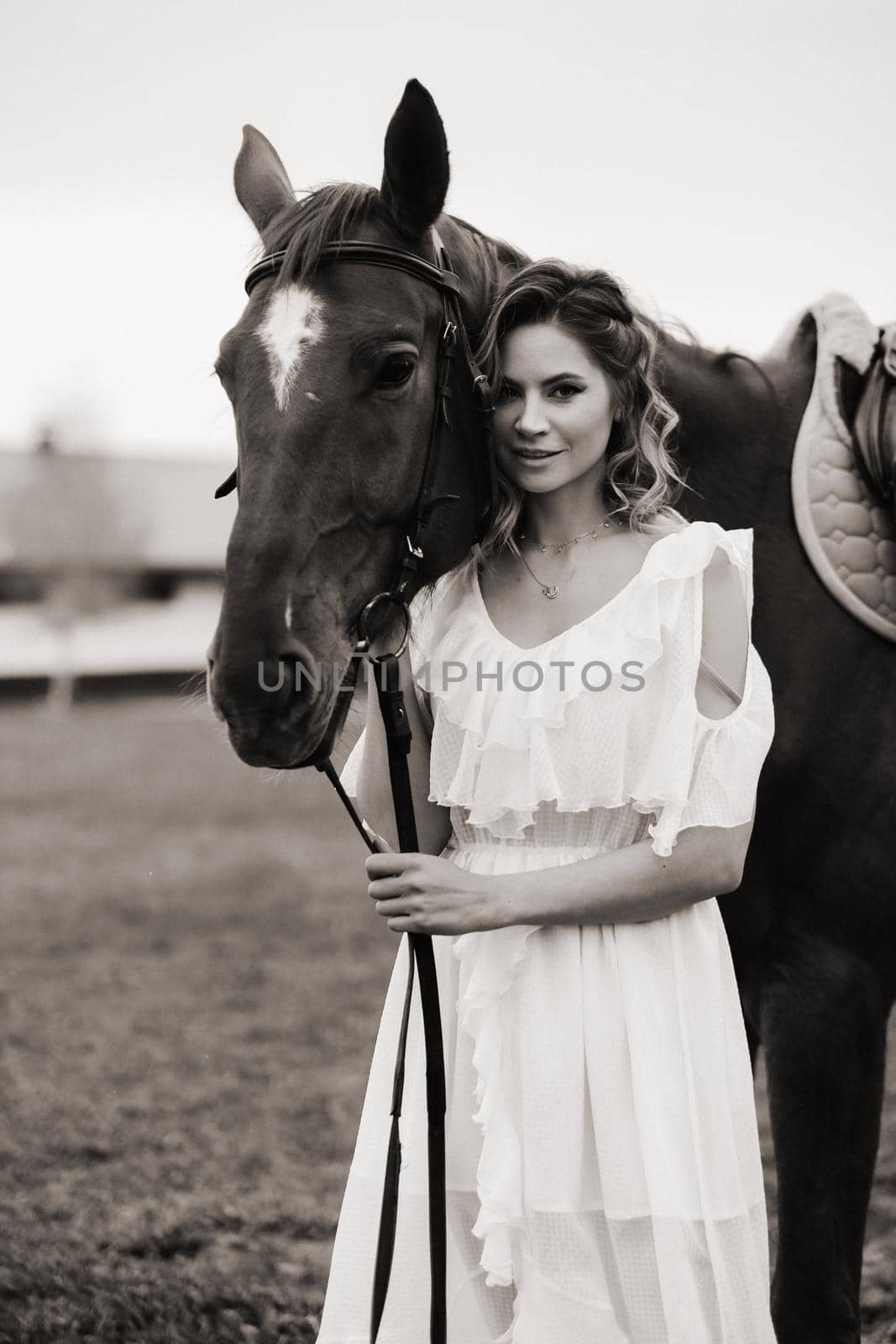 Beautiful girl in a white sundress next to a horse on an old ranch. black and white photo by Lobachad