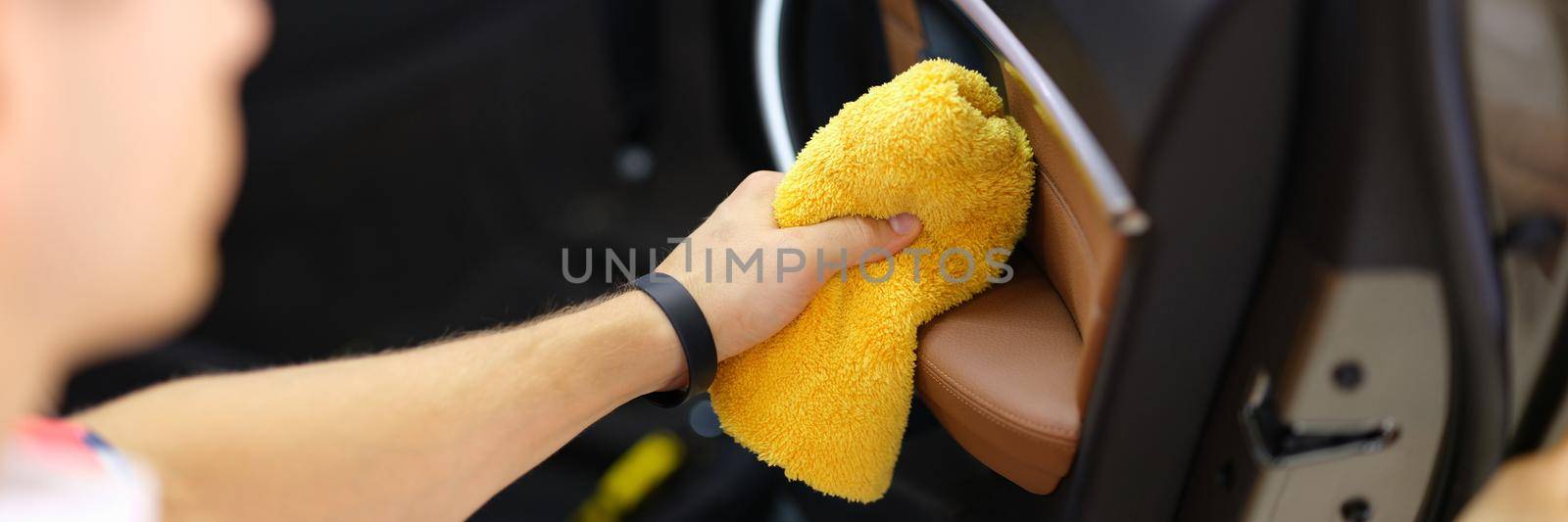 A man wipes a car door with a towel by kuprevich