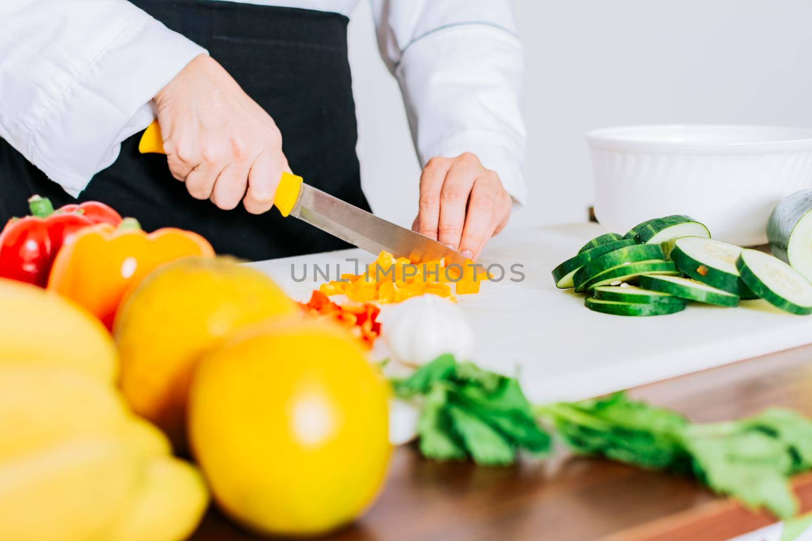 Close up of a female chef cutting vegetables, Hands of female chef cutting vegetables, chef hands preparing and cutting vegetables by isaiphoto