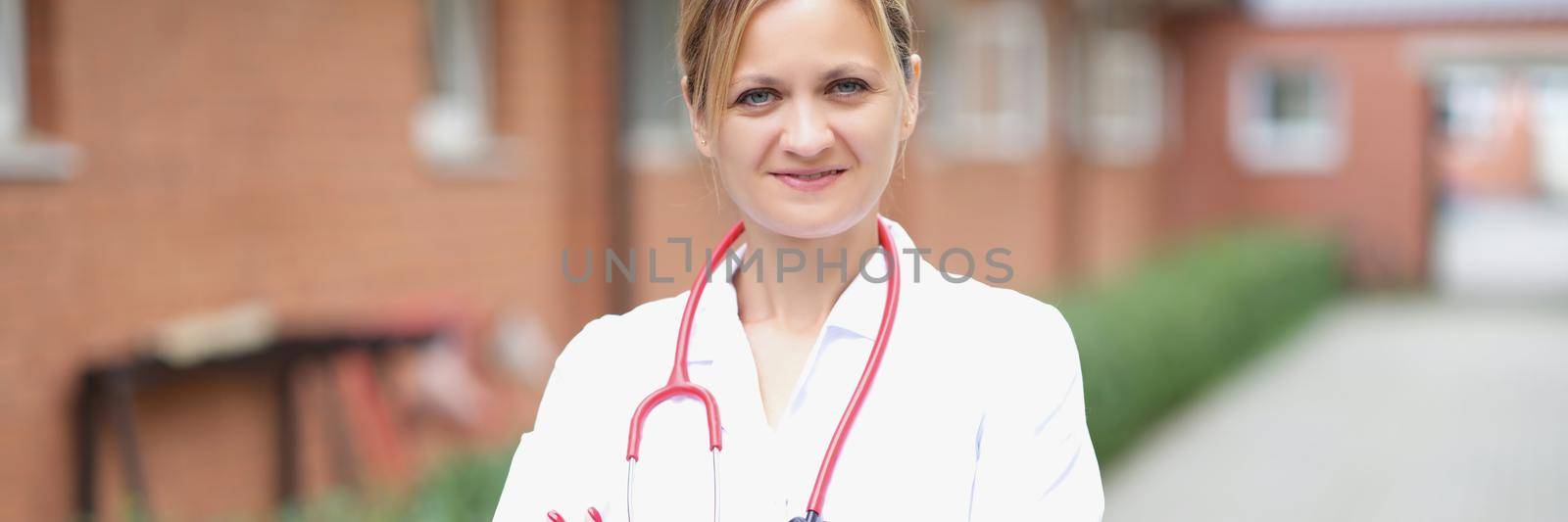 A woman doctor stands on the street near the clinic, close-up, blurry. Rehabilitation center, buildings for the isolation of viral patients