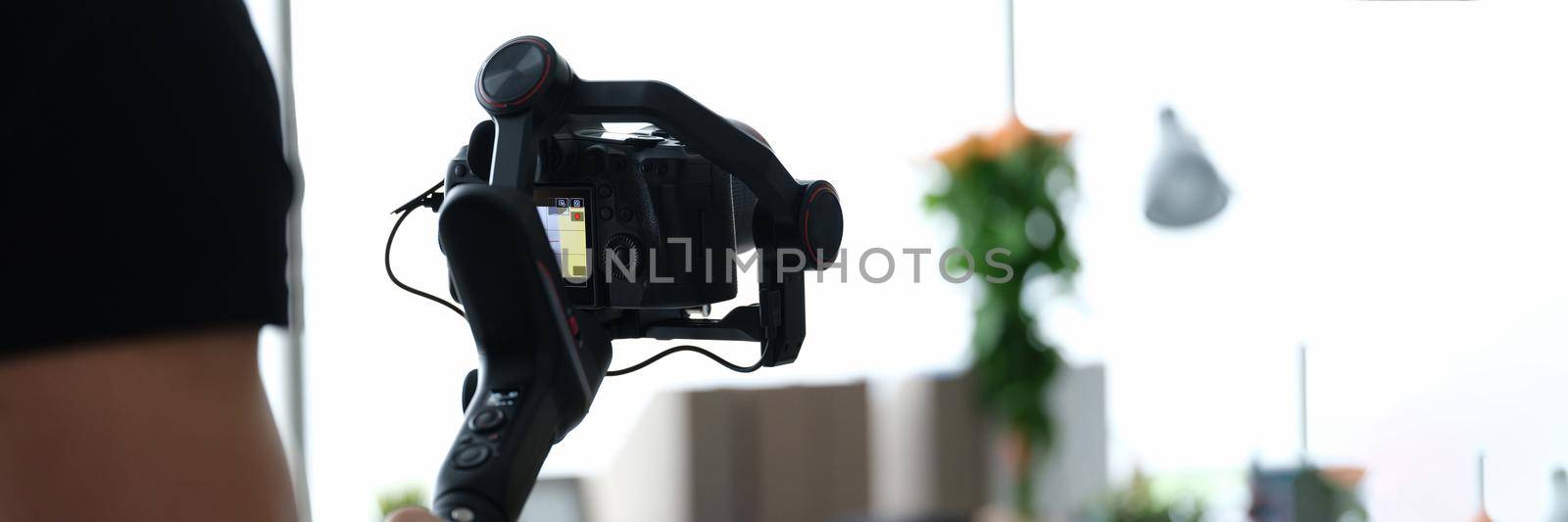 Male photographer with steadicam and camera, close-up, blurry. Professional equipment for photo and video filming, operator