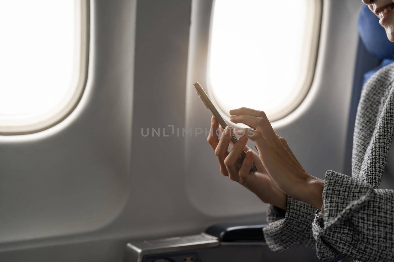 Side view of young businesswoman using smartphone in aircraft, hipster guy holding mobile device for playing or working during flight, business travel concept.