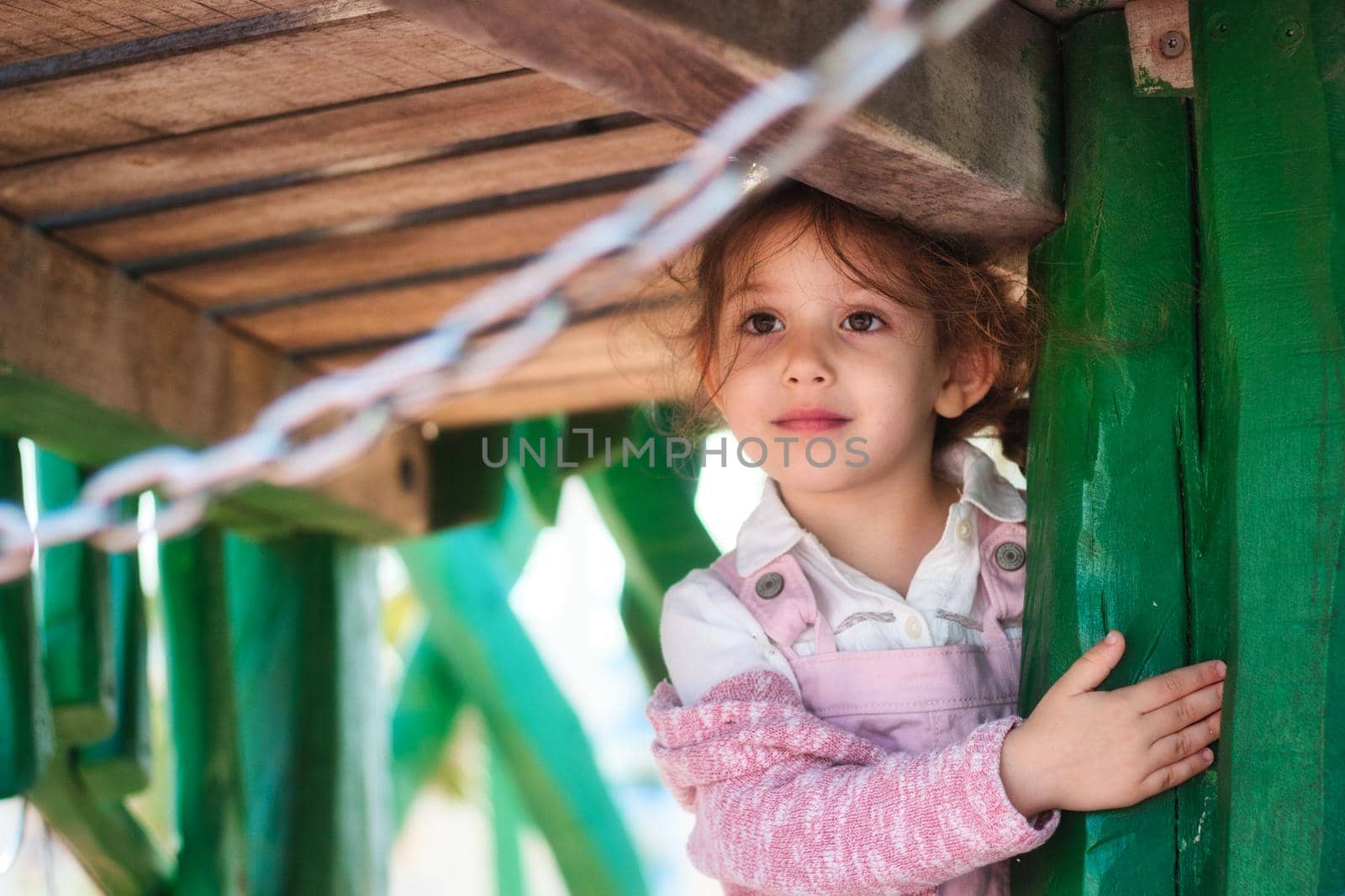 Cute adorable young girl looking thoughtful in a public park play area