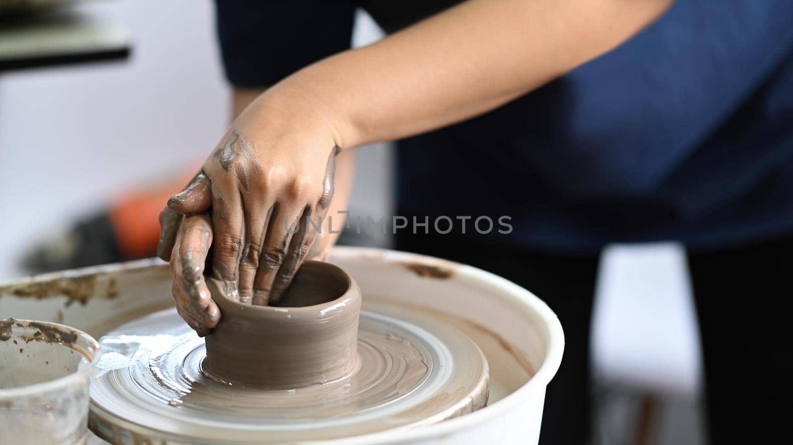 Close up view woman creating handmade ceramic bowl on pottery wheel in workshop. Indoors lifestyle activity, handicraft, hobbies concept.