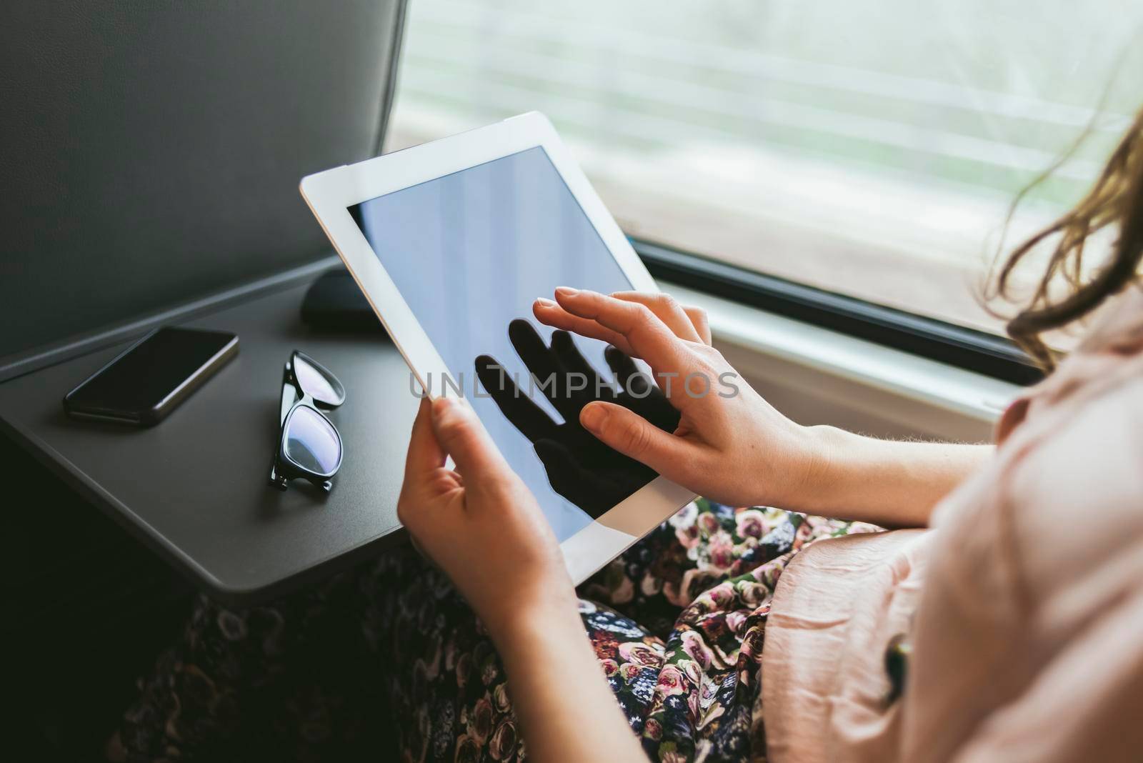 Woman using a digital tablet traveling by train by SimmiSimons