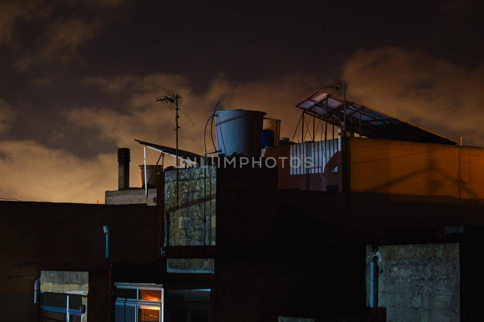 Moody rooftops at night with a cloudy sky in the background