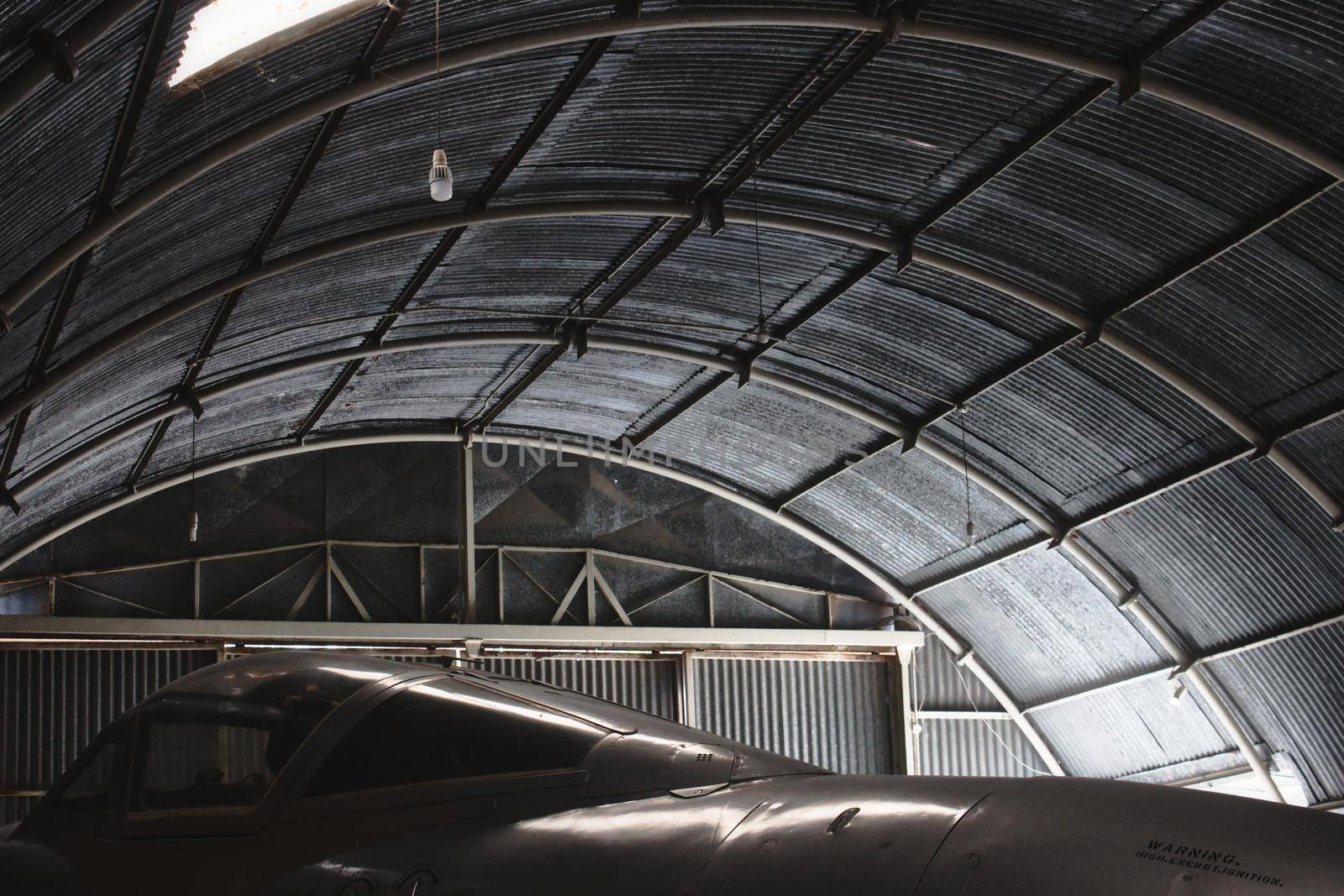Moody shot of a fighter jet aircraft in a big aviation hanger by tennesseewitney