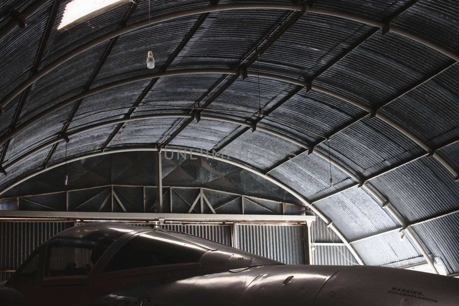 Moody shot of a fighter jet aircraft in a big aviation hanger