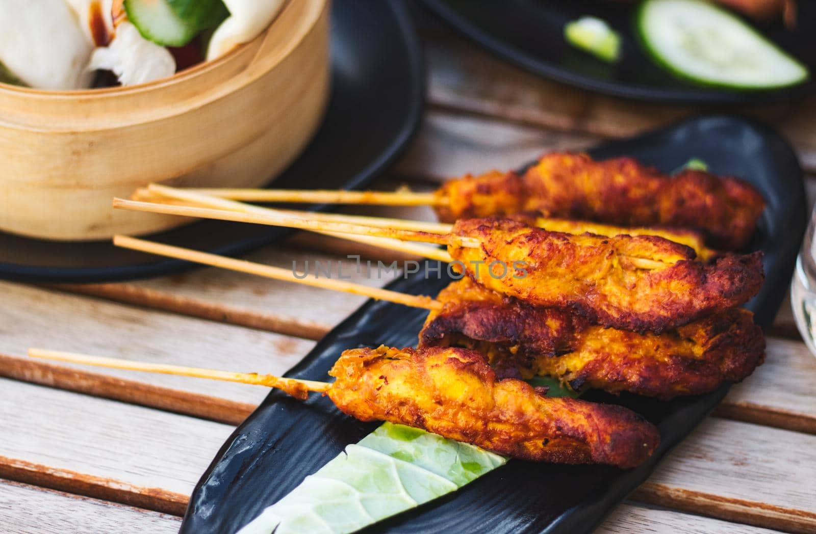 Chicken satay pieces on wooden skewers on a plate by tennesseewitney
