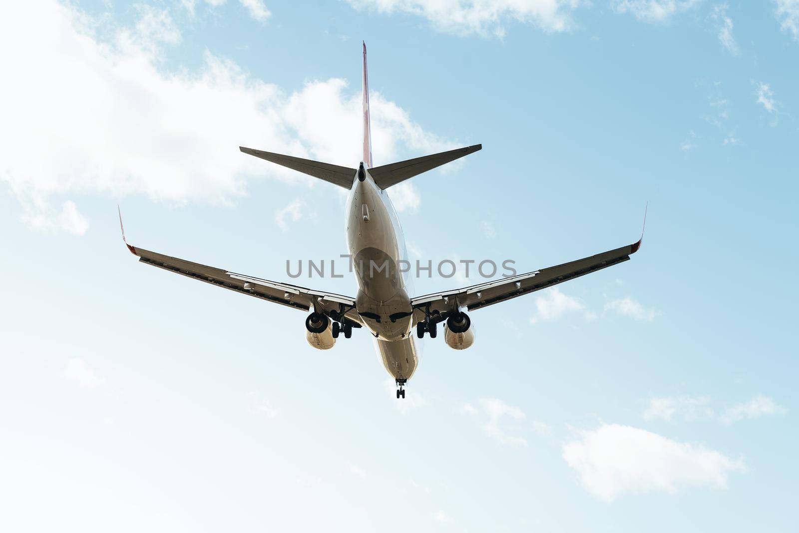 commercial aircraft flying seen from behind with the landing gear deployed, travel concept, copy space for text