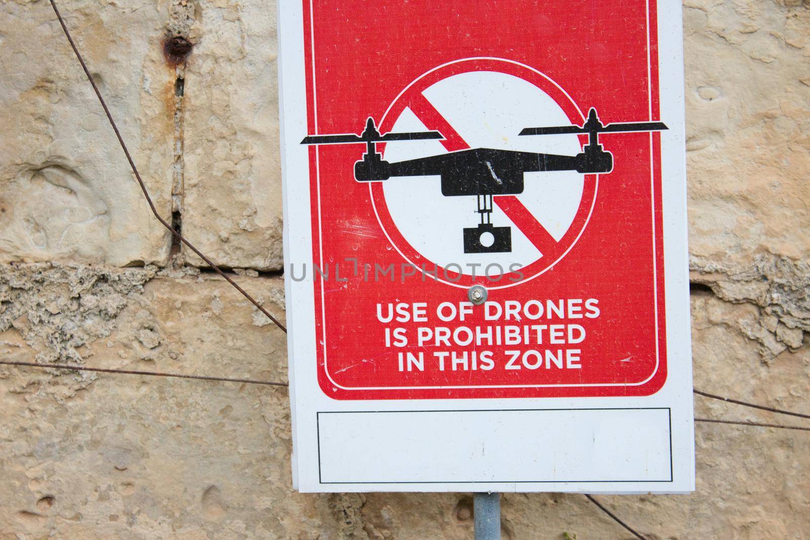 A red sign that reads "Use of drones is prohibited in this zone" against a brick wall